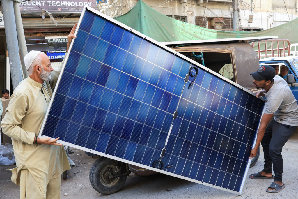 men load solar panels on a rickshaw at a market, in karachi